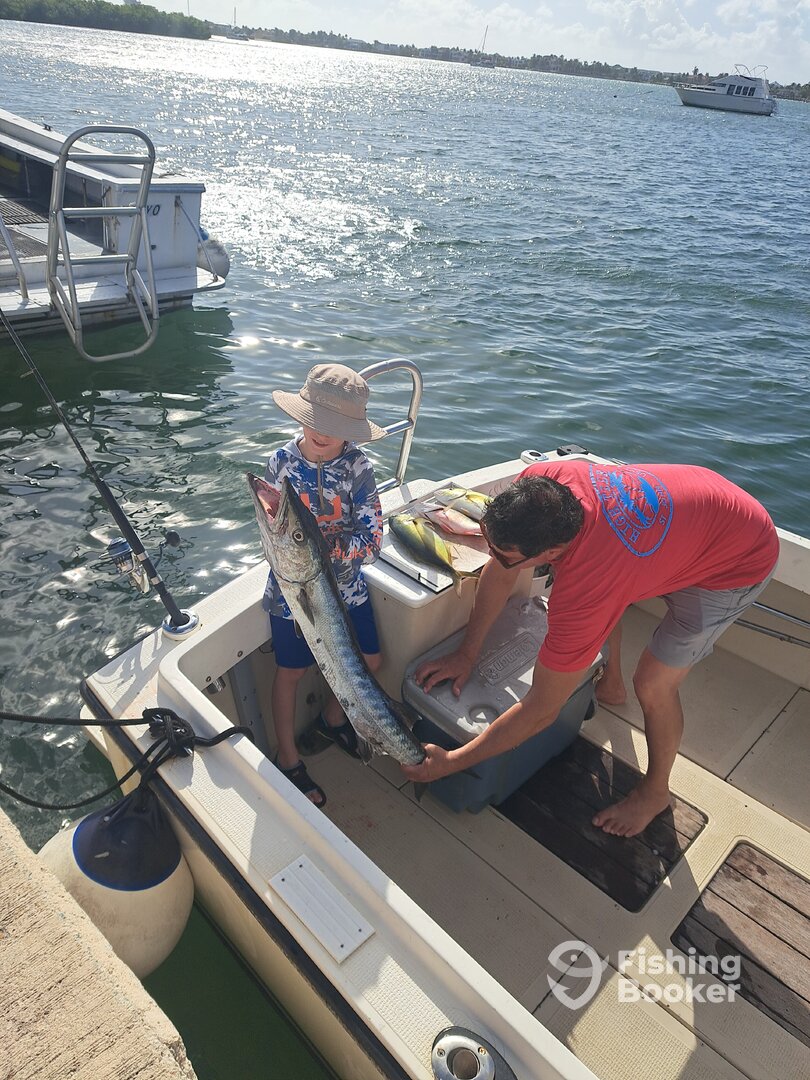 Little man help by his dad with a great barracuda 