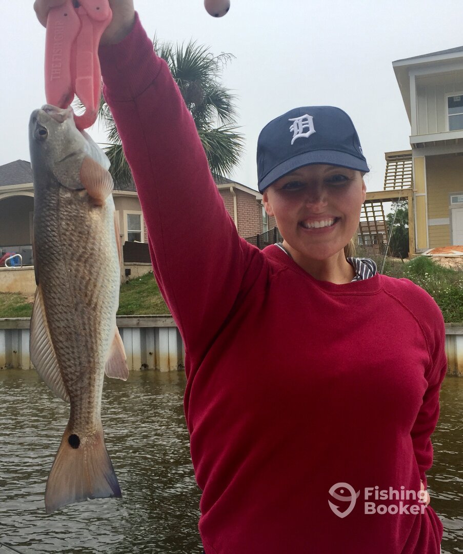 Lady in a red shirt holding up a redfish, Navarre