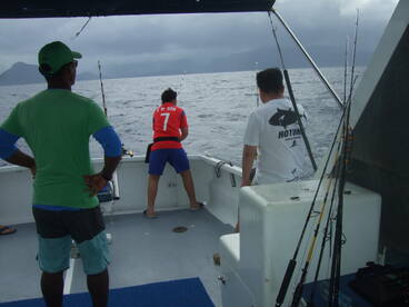 a proud dad watching his son reeling in a tuna