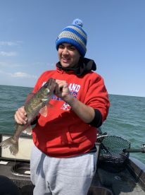 A young angler proudly displaying a Walleye while fishing on a boat, showcasing a beautiful day on the water.