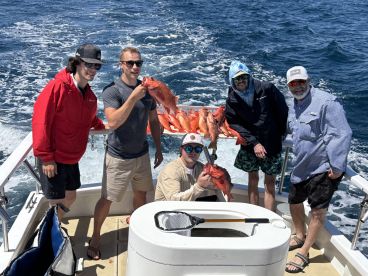 Group of anglers proudly displaying their catch of Red Snapper on a fishing charter in open waters.
