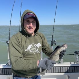 An angler proudly displaying a freshly caught Walleye while fishing on a boat, showcasing the excitement of a successful day on the water.