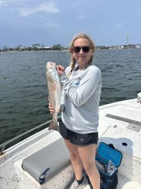 Young angler proudly holding a large Redfish while on a boat, showcasing a successful fishing trip.
