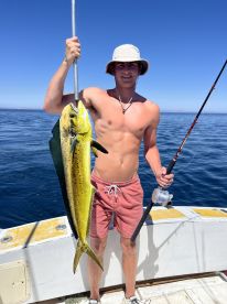 A young angler proudly displaying a vibrant Mahi Mahi while fishing offshore, showcasing a sunny day on the water.