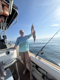 An angler proudly displaying a caught fish while aboard a boat in calm waters, showcasing a successful fishing trip.