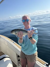 An angler proudly displaying a caught fish while on a boat in calm waters, showcasing a successful fishing trip.