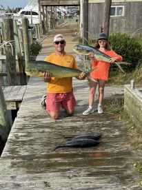 A proud father and daughter duo displaying their catch of Mahi Mahi on the dock after a successful fishing trip.