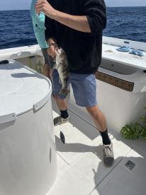 A young angler reeling in a fish while fishing on a boat in open water, showcasing the excitement of the catch.
