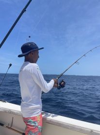A young angler actively reeling in a fish while fishing offshore, showcasing the excitement of the sport.