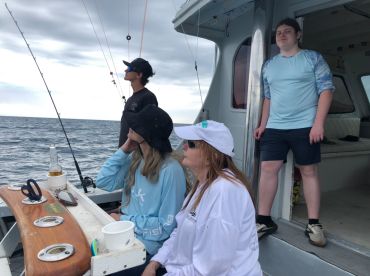 Group of anglers enjoying a fishing trip aboard a charter boat, with a focus on the interior seating and fishing rods.