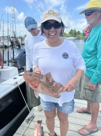 A happy angler proudly displaying a large Grouper caught during a fishing trip at the marina.
