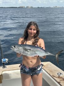 Young angler proudly holding a large fish while on a boat in open water, showcasing a successful fishing trip.