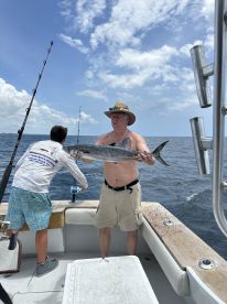 An angler proudly displaying a large fish on a fishing boat, enjoying a day out on the water.
