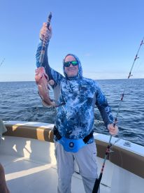 An angler proudly displaying a Red Snapper while fishing on a boat in open waters.