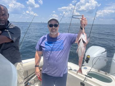 An angler proudly displaying a freshly caught Red Snapper while fishing on a boat in open waters.