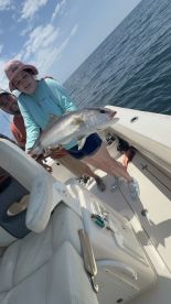Young angler proudly holding a large fish on a boat during a fishing trip.