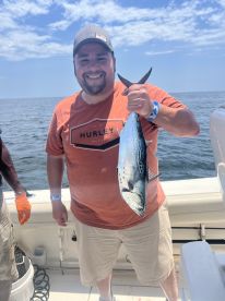 An angler proudly displaying a freshly caught fish while aboard a fishing charter in open waters.