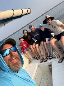 A cheerful family enjoying their time on a fishing boat, showcasing a relaxed atmosphere with kids and adults ready for a day on the water.