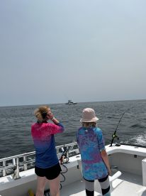 Two young anglers casting lines from a boat, enjoying a day of fishing on the open water.