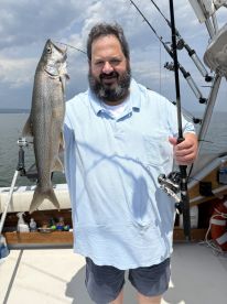 An angler proudly displaying a large Lake Trout while fishing on a boat, showcasing a successful day on the water.