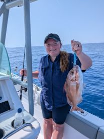 Angler proudly displaying a Snapper caught while fishing offshore, showcasing a beautiful day on the water.