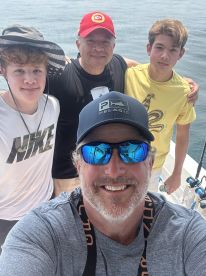 A group of four individuals posing for a selfie on a fishing boat, enjoying a day out on the water.