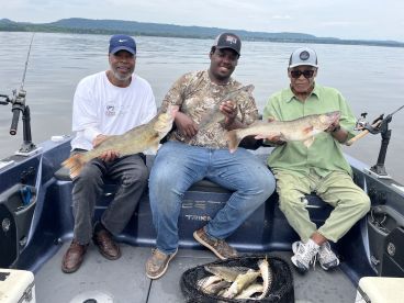 Three anglers proudly displaying their catch of Walleye while fishing on a lake, showcasing a successful day on the water.