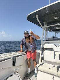 An angler proudly displaying a freshly caught fish while aboard a boat in open waters, showcasing a sunny day fishing experience.