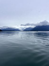 Scenic view of a tranquil fishing environment with snow-capped mountains in the background, showcasing the serene waters of a remote fishing location.