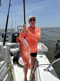 An angler proudly displaying a large Red Snapper while fishing on a boat in open waters.