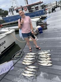 A smiling angler proudly displaying a catch of multiple fish on the dock after a successful fishing trip.