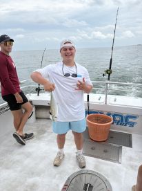 Young angler proudly displaying a caught fish aboard a fishing charter in a coastal environment.