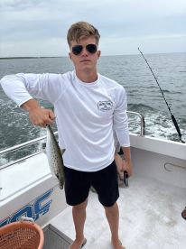 A young angler proudly displaying a Speckled Trout while fishing on a charter boat.