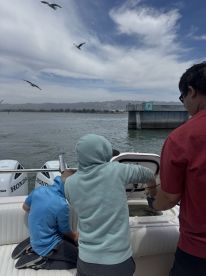 Two young anglers are actively engaged in fishing on a boat, preparing to catch fish while enjoying a day on the water.