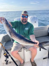 Angler proudly displaying a large Cobia while fishing offshore, showcasing a successful day on the water.