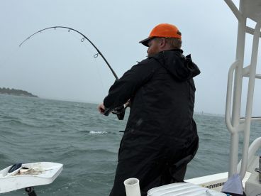 Angler reeling in a catch while fishing in rough waters, showcasing the excitement of the sport.
