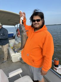 An angler proudly displaying a large Blue Catfish while fishing on a boat, showcasing a successful day on the water.