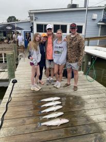 A family poses on the dock with their catch of striped bass after a successful fishing trip.
