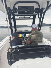 A young angler and an adult captain navigate a fishing boat, showcasing the helm and seating area while preparing for a day on the water.