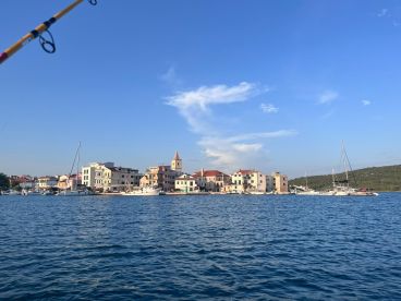 A scenic view of a coastal town with colorful buildings and boats, captured from a fishing boat on a clear day.