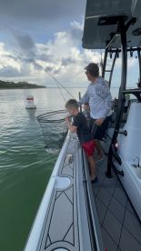 A young boy and an adult are actively fishing from a modern boat, with a net in the water, showcasing an engaging fishing experience.