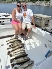 Two anglers sitting on a boat, proudly displaying a catch of Walleye after a successful fishing trip.