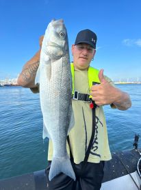 An angler proudly displaying a large striped bass while fishing on a sunny day, showcasing the excitement of a successful catch.