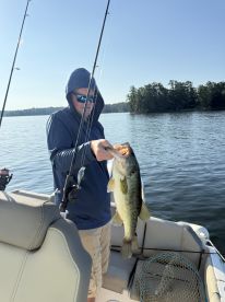 A young angler proudly displaying a large Largemouth Bass while fishing on a serene lake, showcasing a beautiful morning fishing environment.