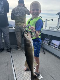 A young angler proudly displaying a large Walleye while fishing on a boat, showcasing the excitement of a successful catch.