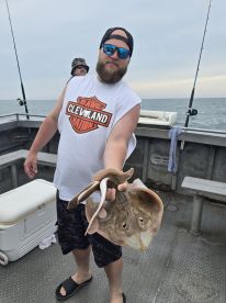 An angler proudly displaying a large stingray while fishing on a charter boat, showcasing the excitement of a successful catch.