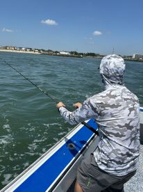 Angler casting a line from a boat in a coastal fishing environment, showcasing a sunny day on the water.