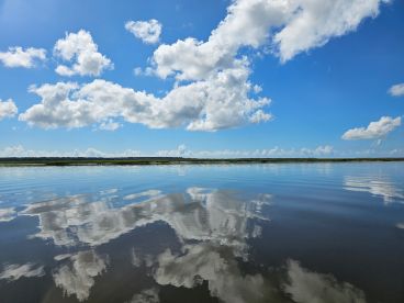 A serene view of calm waters reflecting a vibrant sky, showcasing the tranquil fishing environment.