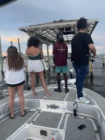 Group of young anglers fishing from a boat near a dock, showcasing a relaxed fishing environment.