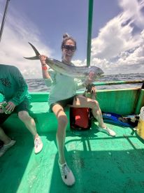 An excited angler proudly displaying a large fish aboard a vibrant green fishing boat, enjoying a sunny day on the water.